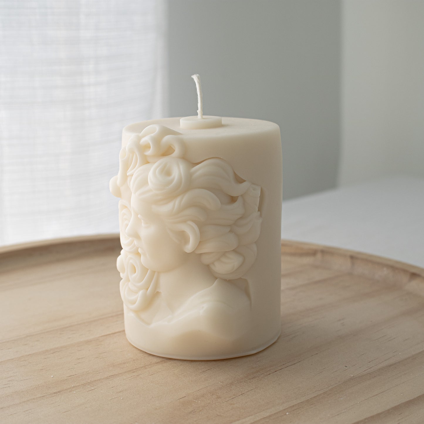 Ivory candle featuring an intricate Mediterranean-inspired relief of a woman’s head