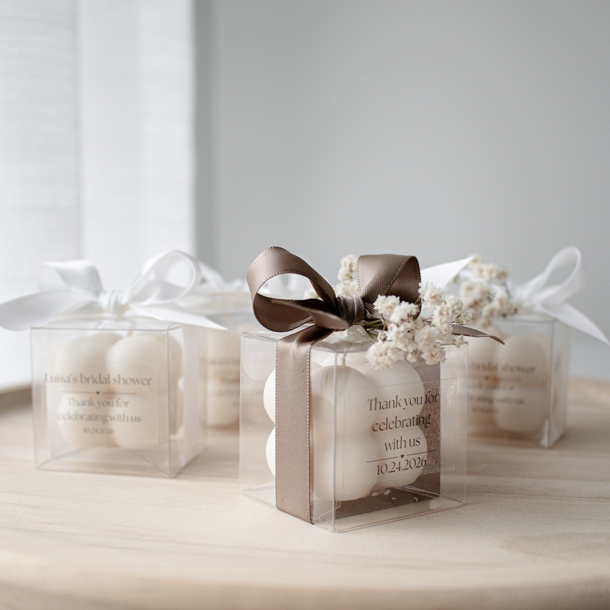 candle favors in a clear gift box with sateen ribbon and dried flowers